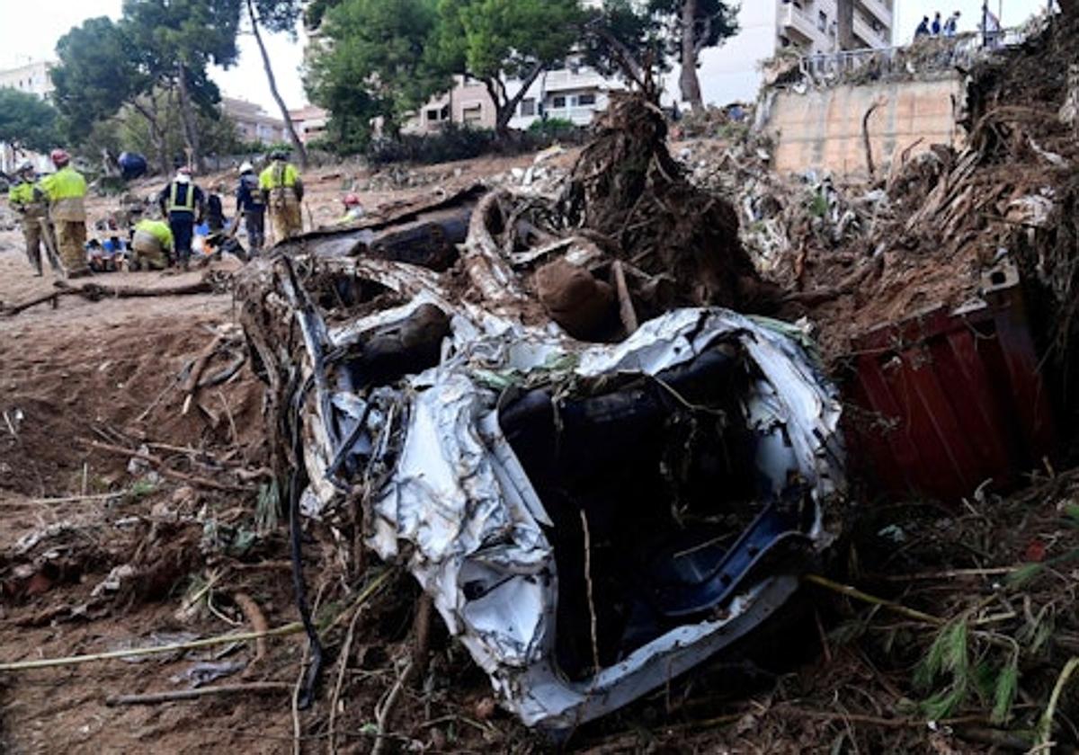 Bomberos retiran restos de coches en la orilla de un río en Paiporta.