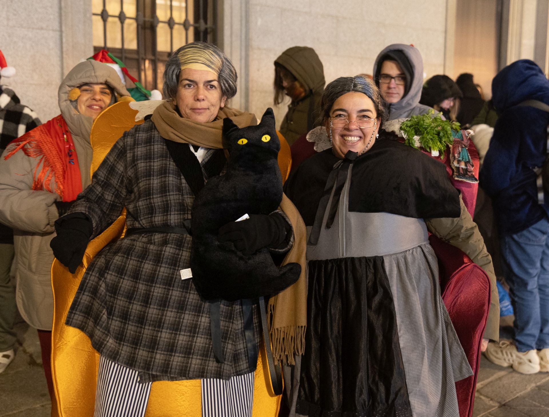 Dos personas disfrazadas hacen cola antes de pasar a la celebración del Sorteo Extraordinario de la Lotería de Navidad 2024, en el Teatro Real. 