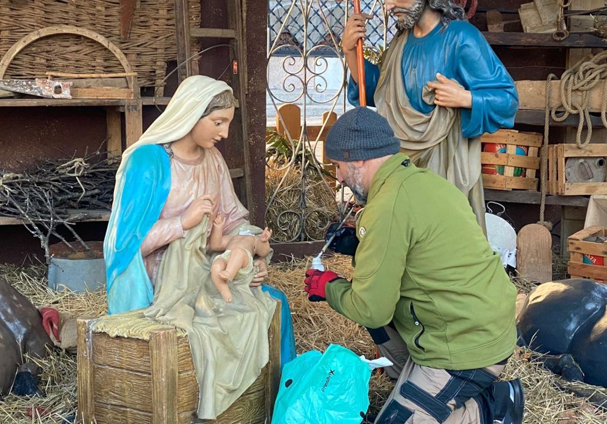 Un hombre coloca la cabeza sobre la figura del niño Jesús.