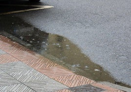 Lluvia ligera sobre un charco en una calle de León.