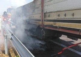 Un bombero de la Diputación de León sofoca el incendio en los bajos de un camión en la A-6 en León.