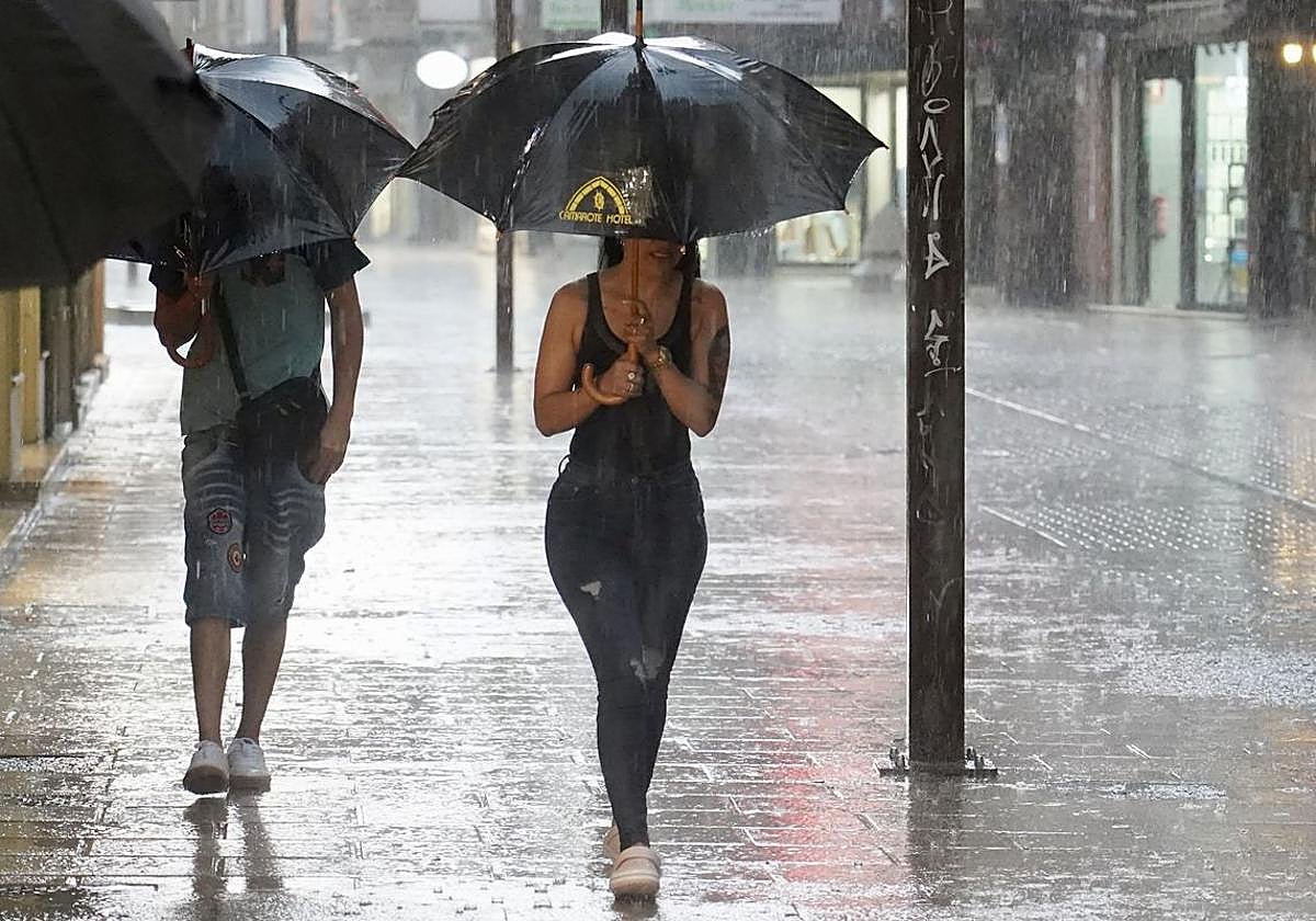 Una mujer camina por una calle de León durante una tormenta.