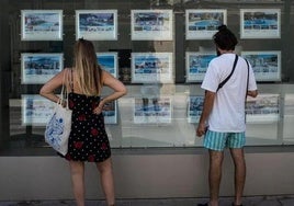 Dos personas revisan las opciones de alquiler de una inmobiliaria.