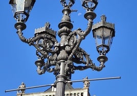 La luna vista entre los brazos de una farola de la Plaza Mayor de León.