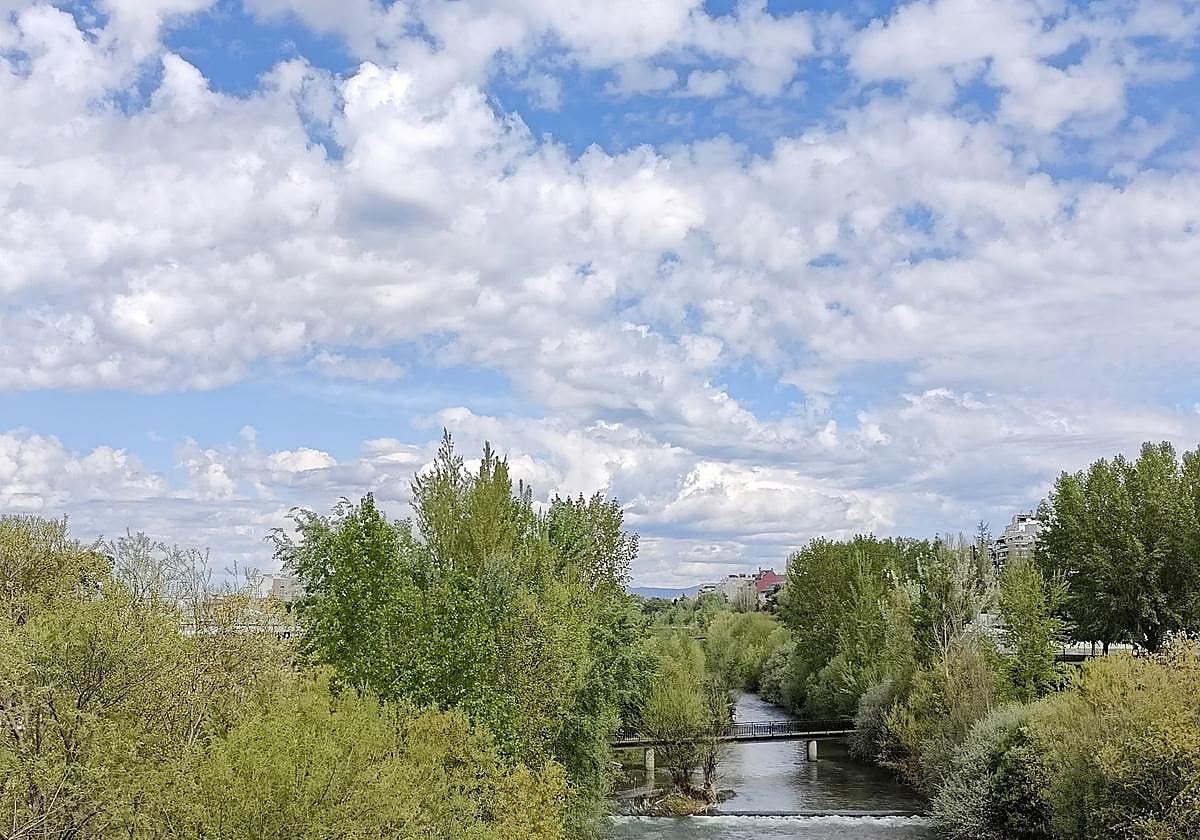 Cielo con nubes y claros visto desde una pasarela sobre el río Bernesga en León.