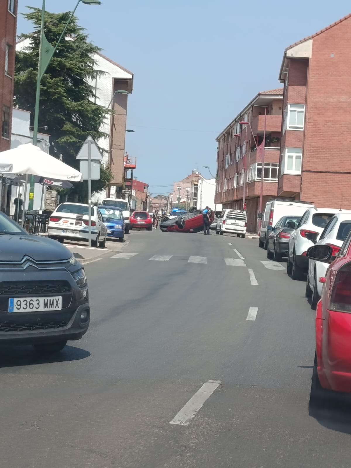 Un coche volcado corta un carril en una calle de Trobajo del Camino.