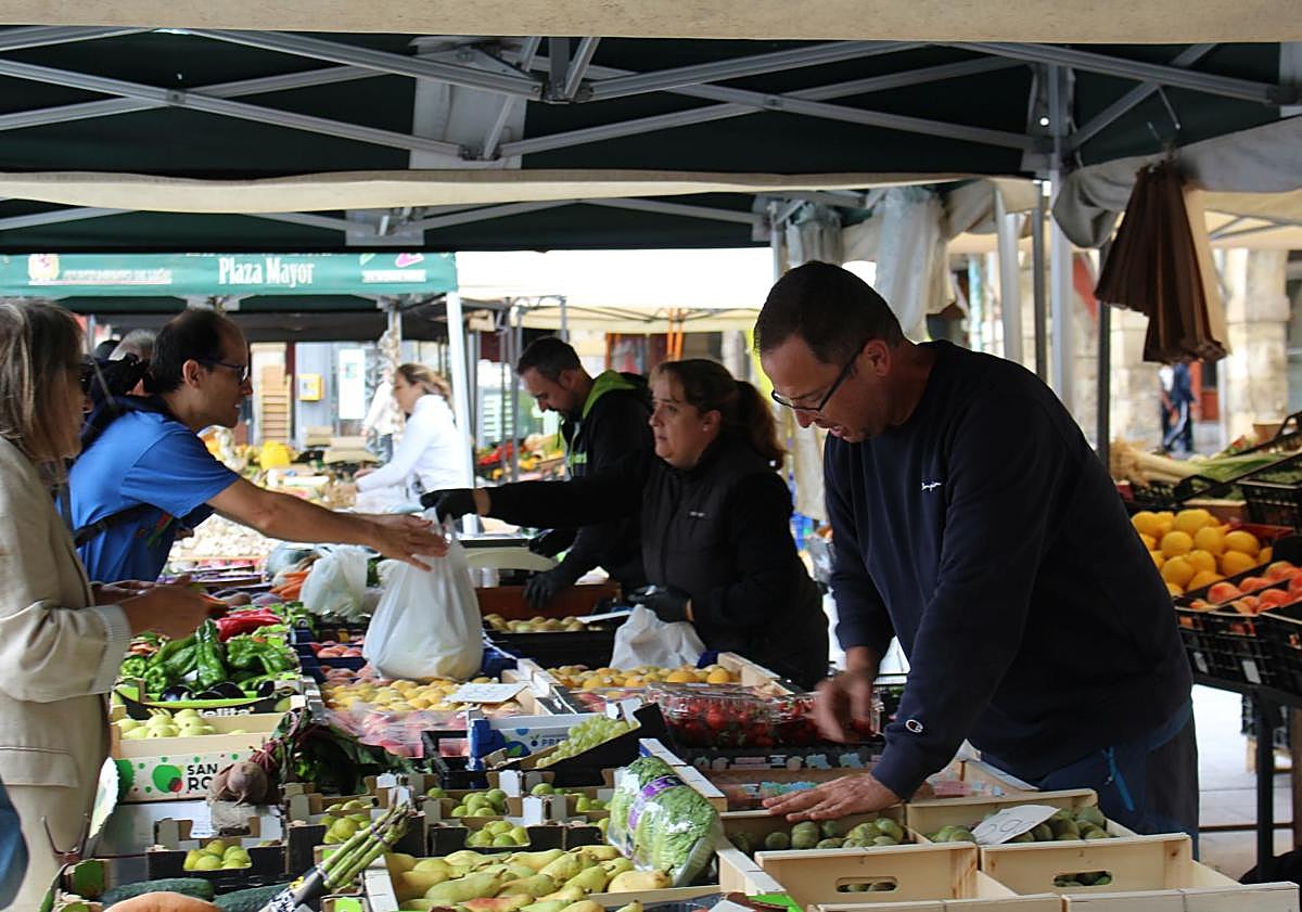Imagen principal - Valeriano Calleja, Diego Santiago y Alberto Arias en sus puestos en el mercado de la plaza Mayor de León.