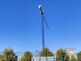 La Luna asoma entre dos grúas de construcción en el barrio leonés de La Lastra.