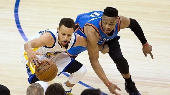 Stephen Curry y Russell Westbrook pelean por el balón. 