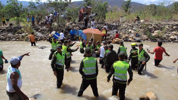 Cientos de colombianos cargan sus pertenencias por el río Táchira.