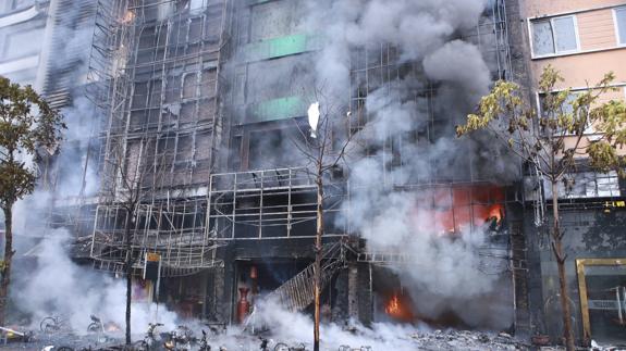 Un grupo de bomberos trabaja en las labores de extinción de un fuego en un karaoke de Hanoi, Vietnam.