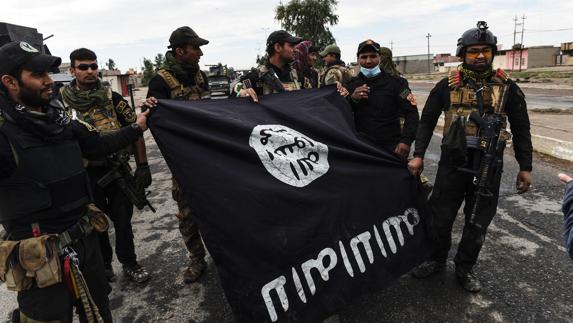 Soldados iraquíes posan con una bandera del Daesh en una aldea conquistada a los yihadistas.