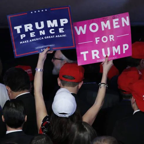 Una mujer muestra carteles de apoyo a Donald Trump.