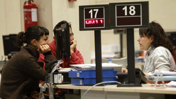 Una funcionaria atiende a dos jóvenes en una oficina de empleo.