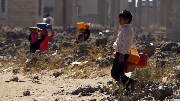 Niños yemeníes transportan agua en Saná.