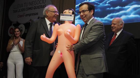 Luis Felipe Céspedes (d), ministro de Economía chileno, recibe de parte de Roberto Fantuzzi una muñeca hinchable.