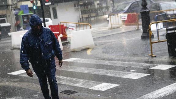 Un hombre camina bajo un fuerte aguacero en Valencia.