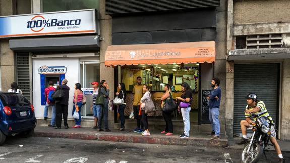 Un grupo de personas hace fila en una entidad bancaria de Caracas.