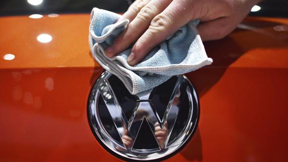 Un empleado limpia el logotipo de un coche Volkswagen en Alemania. 
