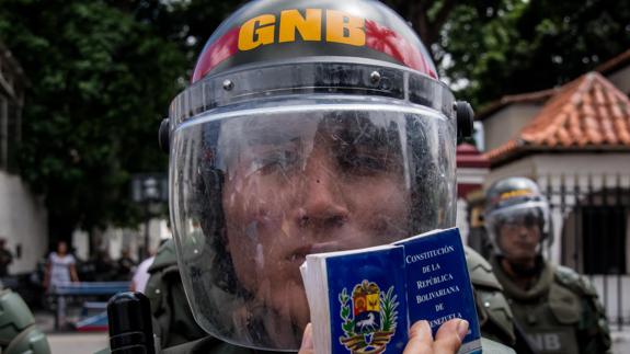 Una mujer sostiene una Constitución Política de Venezuela frente a integrantes de la Guardia Nacional Bolivariana (GNB).