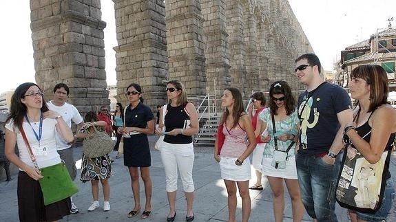 Una guía informa a un grupo de turistas en la plaza del Azoguejo, en Segovia..