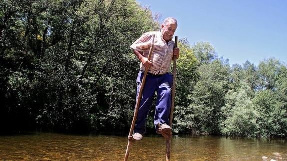 Pepín, presidente de la Junta Vecinal de Trascastro de Luna, utiliza unas zancas para atravesar el río Omaña