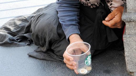 Un mendigo pide monedas en plena calle.