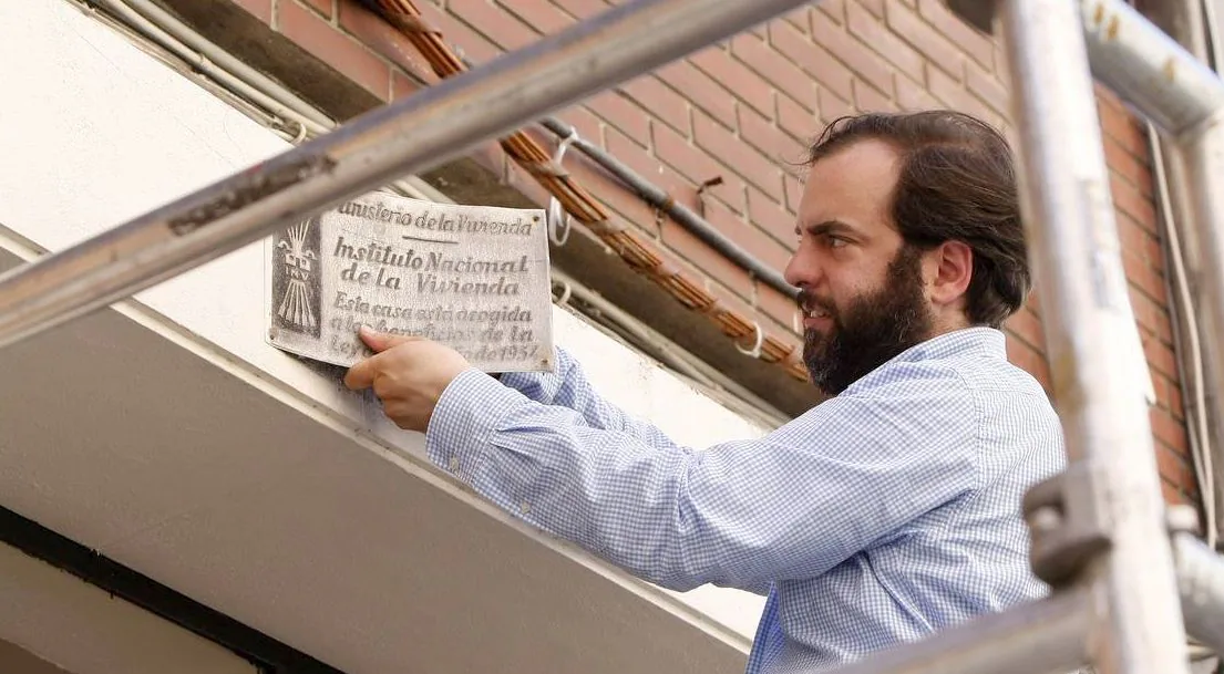 Un operario retira una placa del Instituto Nacional de la Vivienda.