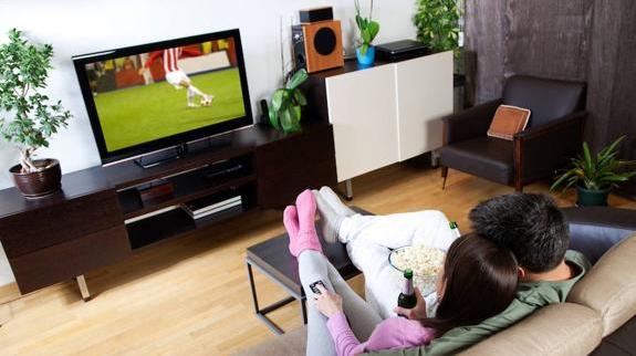 Una pareja ve la tele en el salón de su casa.
