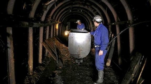 Dos mineros extraen carbón de un pozo.