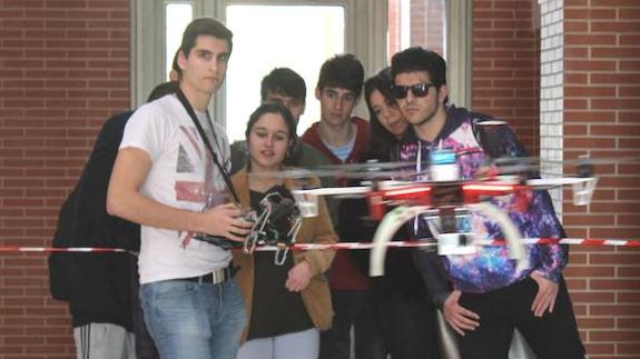 Varios alumnos de Ingeniería contemplan cómo se maneja un dron. 