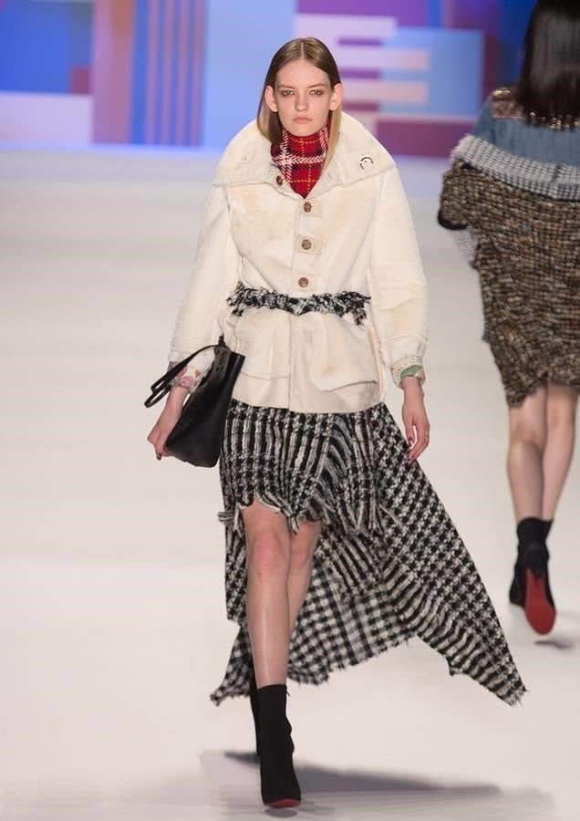 Falda asimétrica de cuadros combinada con abrigo color crema.