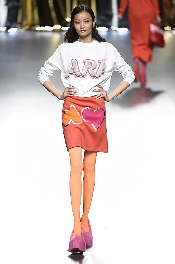 Falda naranja con corazones y sudadera blanca.