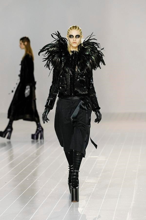 Un look en negro con cazadora con plumas, guantes de cuero, falda hasta la rodilla y plataformas.