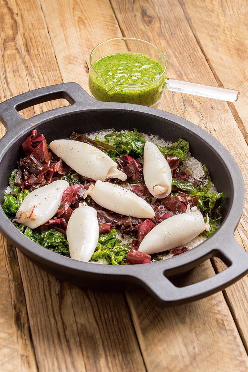 Para dos personas: Limpia 300 g de chipirones, quítales los tentáculos y las aletas y ponlas dentro del cuerpo como relleno. Mezcla 500 g de sal marina gorda con un puñado de algas (mezcla dulces con lechuga de mar) y ponla en una cazuela al fuego. Cuando la sal esté bien caliente, coloca encima unas algas más y los chipirones. Tápala y deja cocinar durante cuatro minutos. Para la salsa, asa las 3 cabezas de ajos envueltas en papel de aluminio al horno a 180 ºC unos 25 minutos. Escalda 10g de perejil unos segundos y pásalo a un bol con agua y hielo. Saca la pulpa de los ajos y tritúrala junto con aceite de oliva y el perejil hasta obtener una salsa muy ligada. Sirve los chipirones acompañados de la salsa y algunas algas.