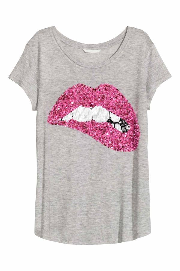 Con labios a base de pailletes, camiseta en color gris (Precio: 14.99 euros).