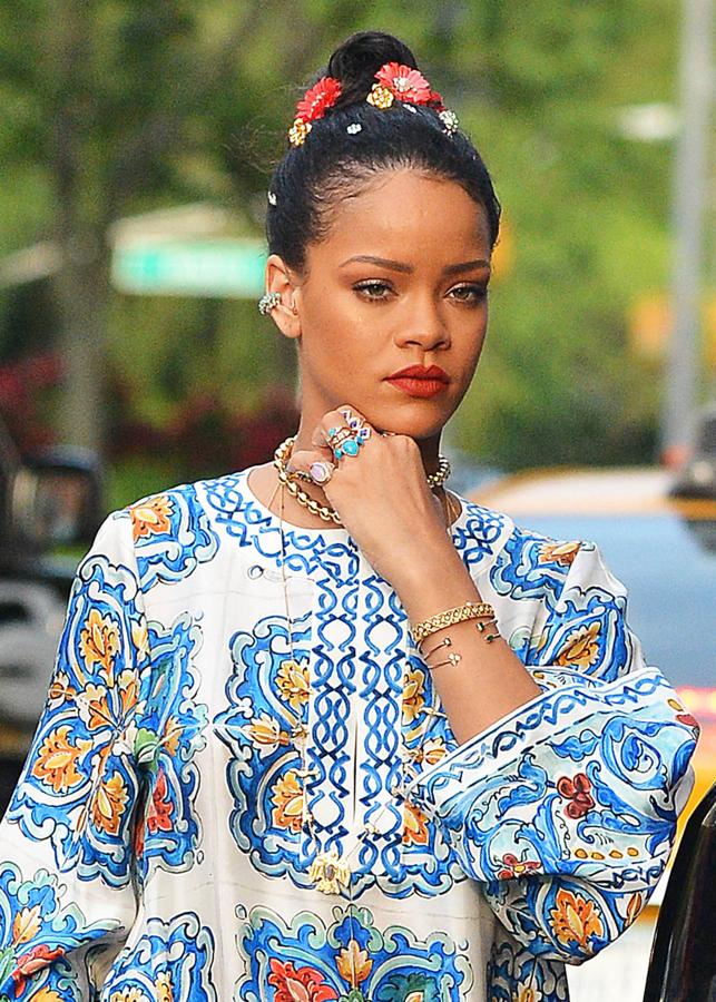 Un peinado perfecto para este verano. Rihanna con moño alto adornado con flores de alegres colores.