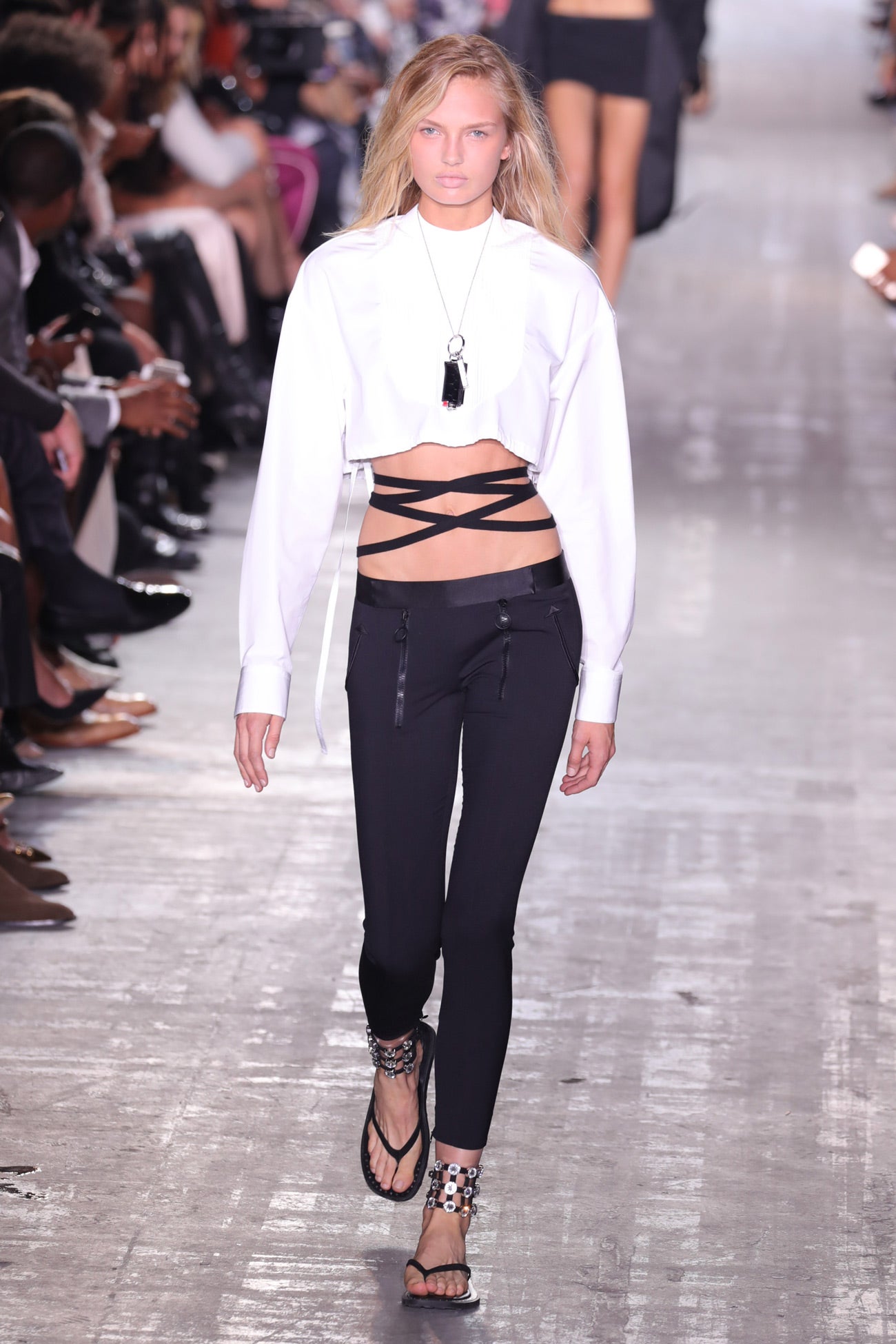 Romee Strijd lucía un clásico look de Alexanger Wang. en blanco y negro, con tiras, dejando ver la tripa con una sudadera corta y sandalias platas con chapas.