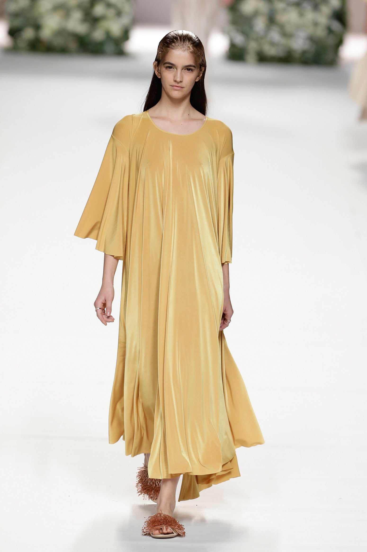 Vestido largo dorado fluido con sandalias en otra tonalidad de dorado.