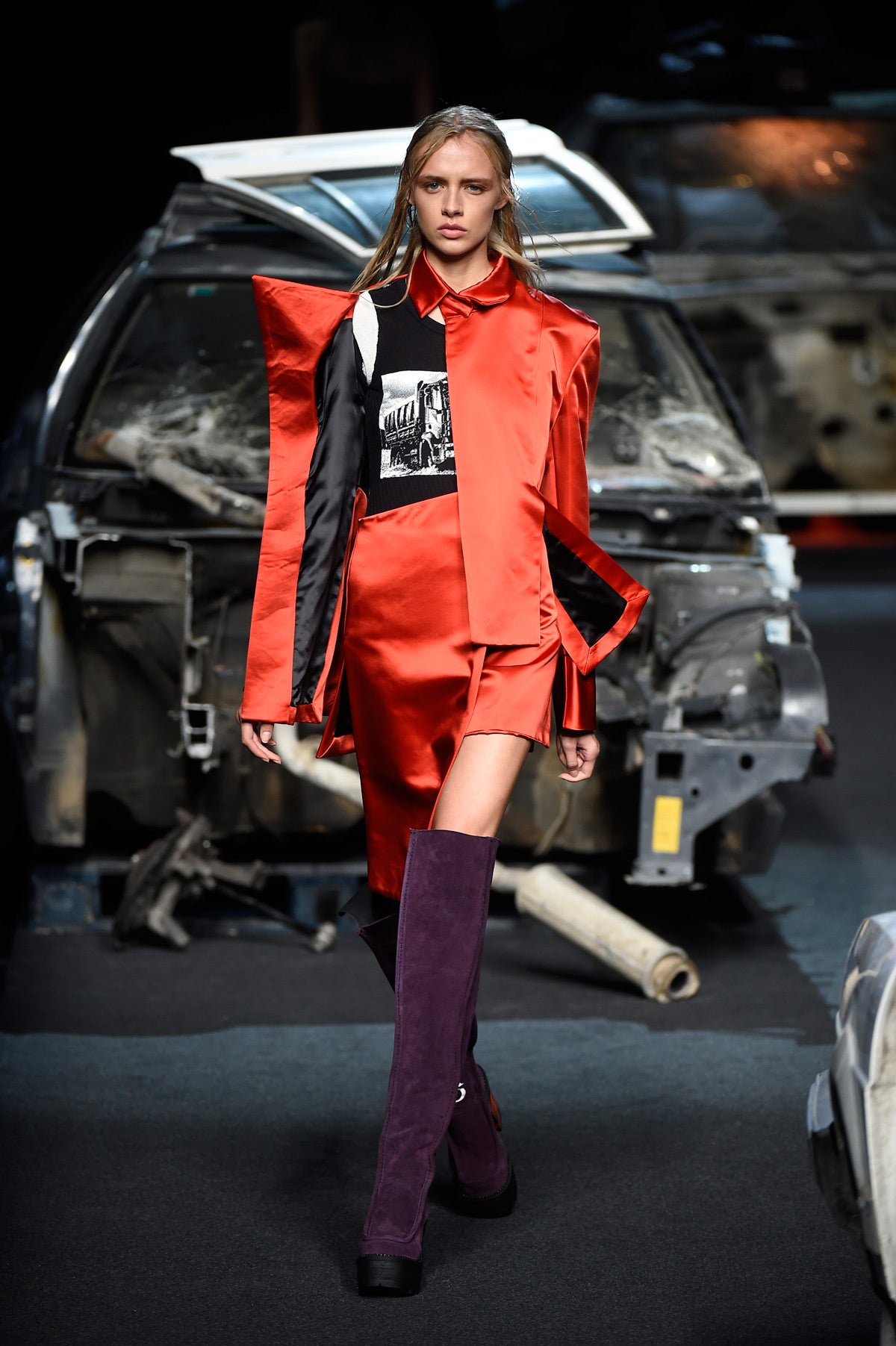 Traje rojo deconstruido conjuntado con botas moradas con un mensaje inscrito.