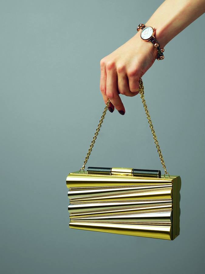 Reloj Catwalk en acero inoxidable bañado en diferentes tonos, de Emporio Armani; y clutch en metal dorado con relieve geométrico, de Sara Battaglia para Salvatore Ferragamo.