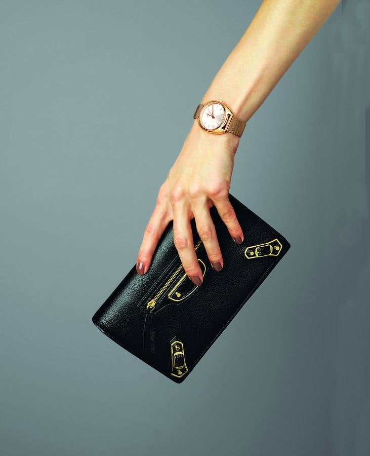Reloj en acero con baño de oro rosa y correa de malla, de Tous; y clutch Metallic Edge en piel negra, de Balenciaga.