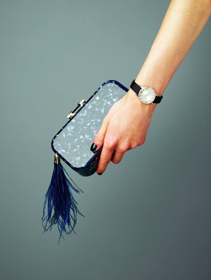 Reloj Atlas, en acero y diamantes con correa de seda, de Tiffany & Co.; y clutch Eva Resin Navy con detalle de pluma de avestruz, de Yliana Yépez.