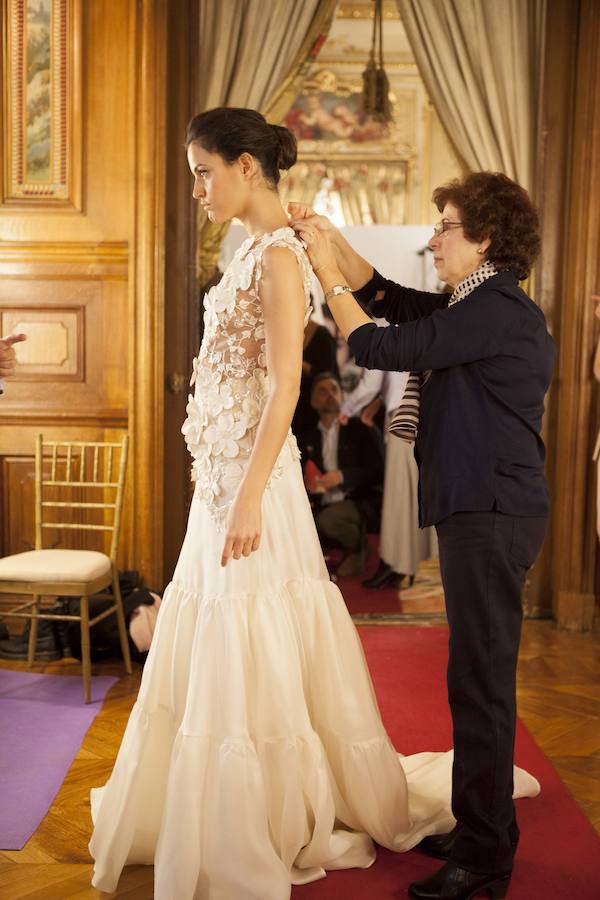 Una modista remata el vestido que lleva una de las modelos para que quede perfecto.