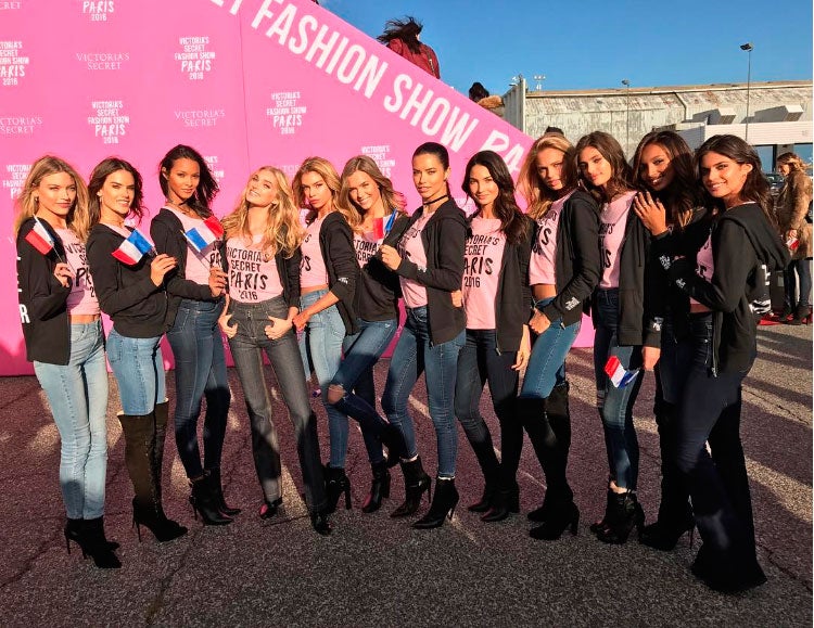 Los ángeles de Victoria's Secret posan con la bandera francesa y y el uniforme "oficial": vaqueros, botas negras, sudadera negra y camiseta rosa de Victoria's Secret.