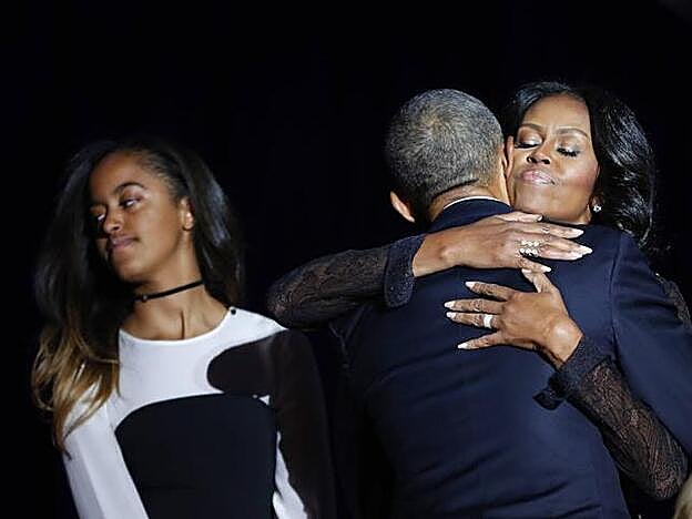 Michelle y Barack Obama en un abrazo y su hija al lado