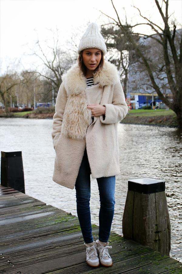 Lizzy vd Ligt con abrigo de pelo blanco, estola de piel y gorro de punto