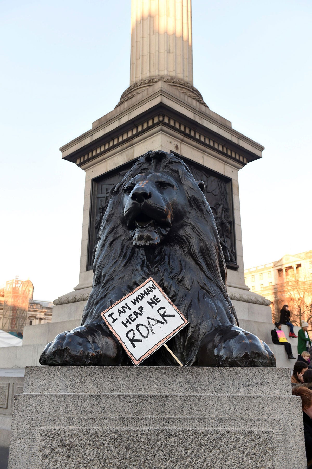 Delante de la estatua del león un cartel con la letra de una canción de Katy Perry: "Soy una mujer. Escúchame rugir".