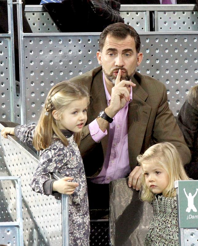 Don Felipe, en un gesto de lo más natural con sus hijas durante un partido de tenis.
