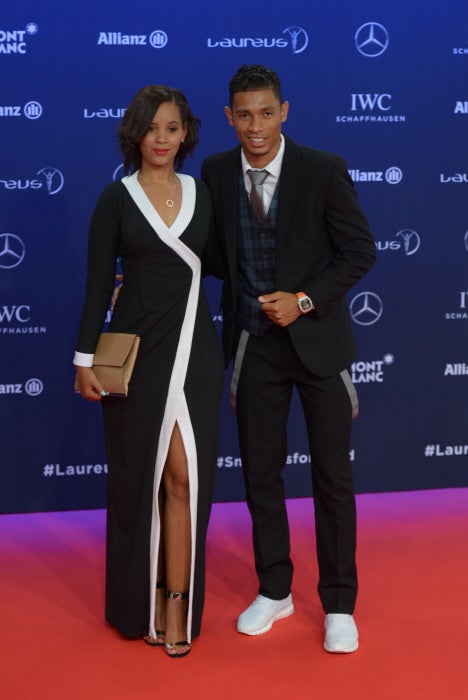 El atleta sudafricano optó por un original traje con chaleco con estampado de cuadros, pantalones con vivos en gris de TM Bespoke Suits y zapatillas blancas, el mismo color que los detalles del vestido negro con abertura de vértigo de su chica Chesney Campbell que firmaba Elmerane van Ryneveld.